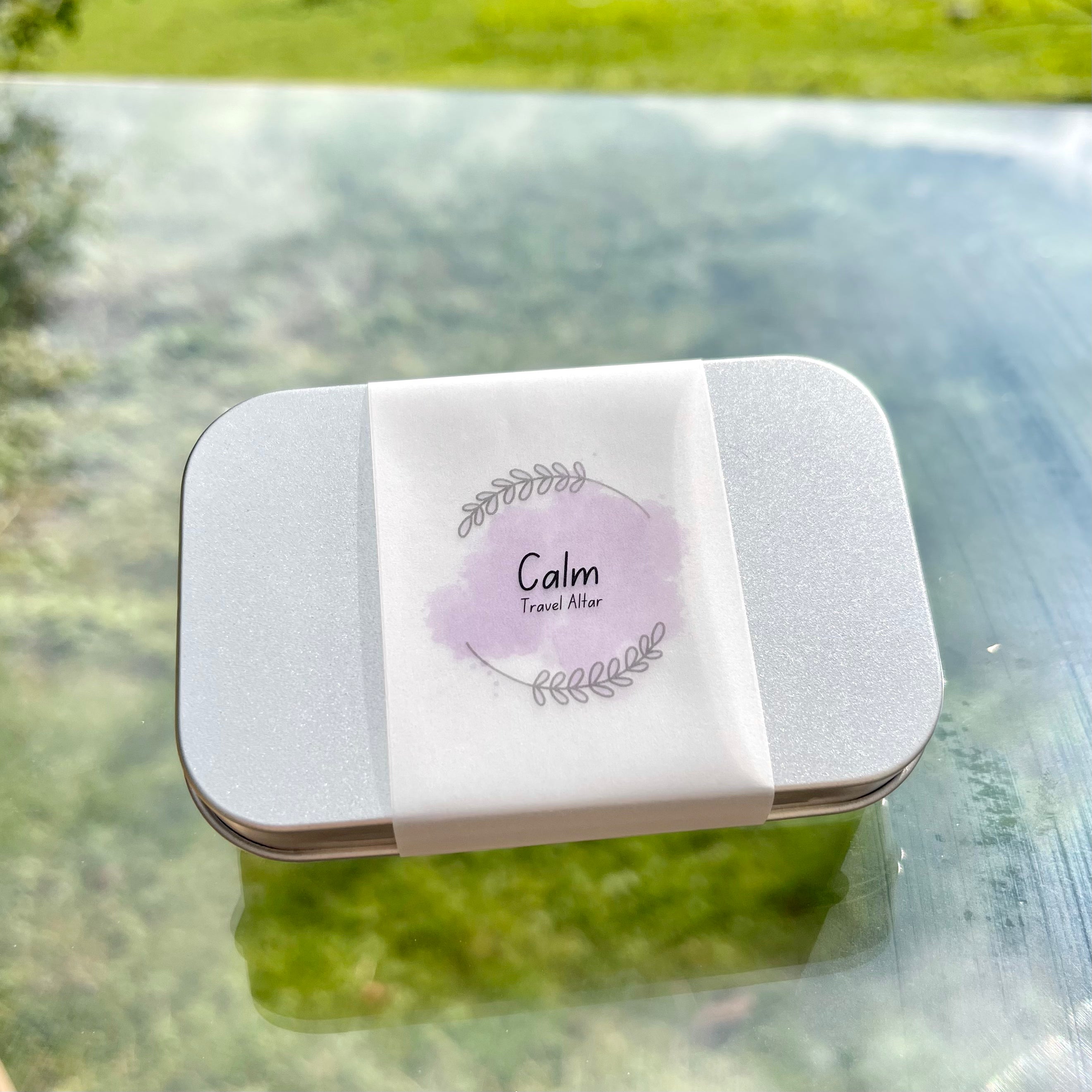 A calm travel altar. A closed metal tin with a paper wrap.