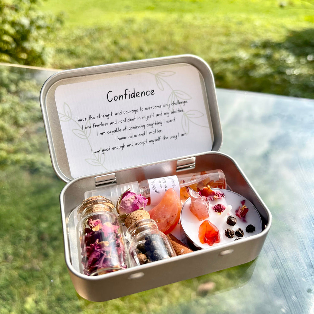 an open metal travel altar tin, inside are 2 jars of herbs, incense, a moon mist, a spell candle and carnelian tumble stone. the theme is carnelian
