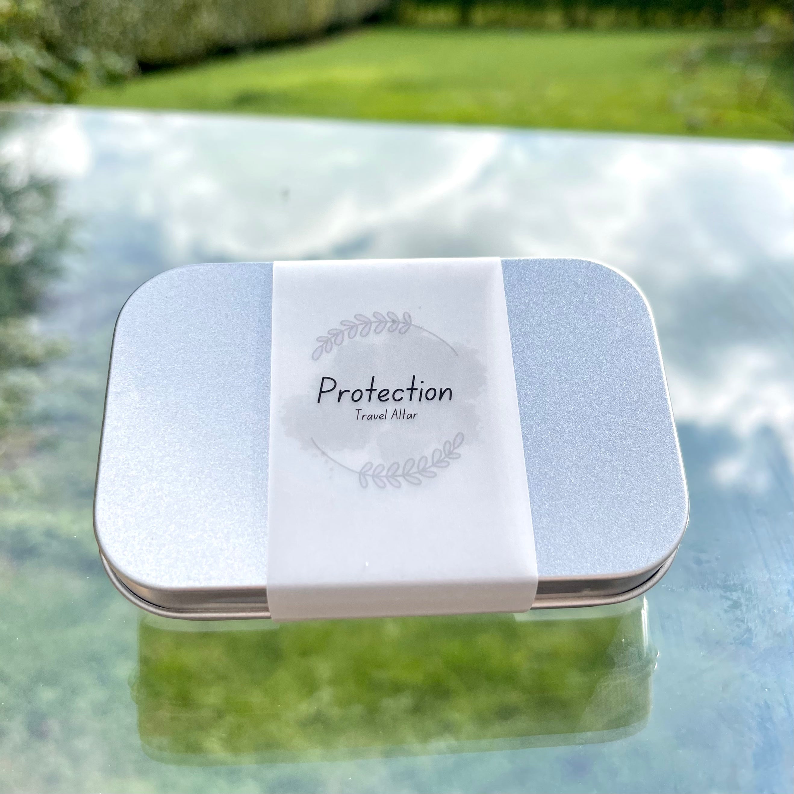 a sealed protection travel altar in a metal tin and a paper wrap